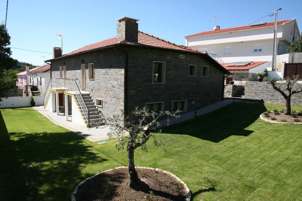 een stenen huis met een boom in een tuin bij Casa do Olival in Macedo de Cavaleiros