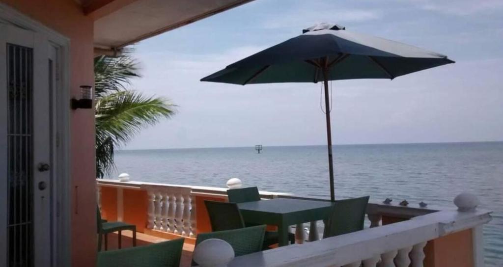 a table and umbrella on a balcony with the ocean at Serdena Homestay Fronting Cuatro Islas in Hindang