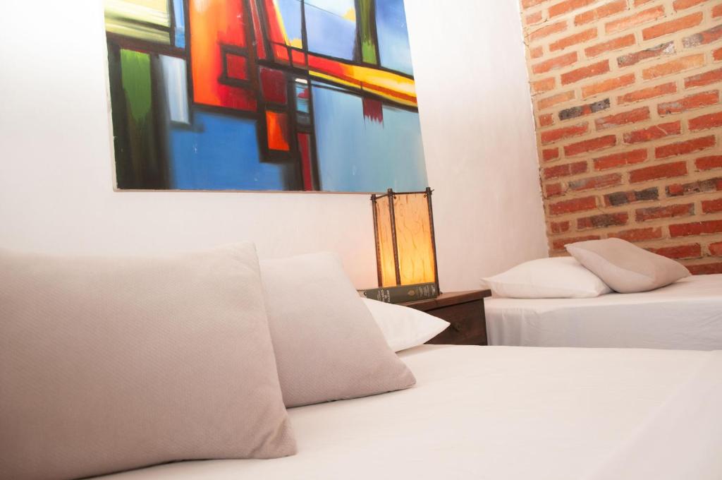 a room with two beds and a painting on the wall at La Juanita Hostel Barichara in Barichara