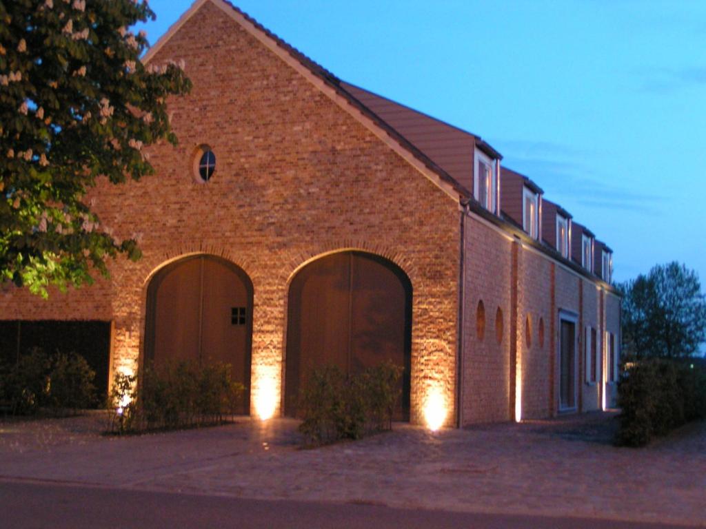 um grande edifício de tijolos com duas grandes portas em B&B Fragaria em Hoogstraten