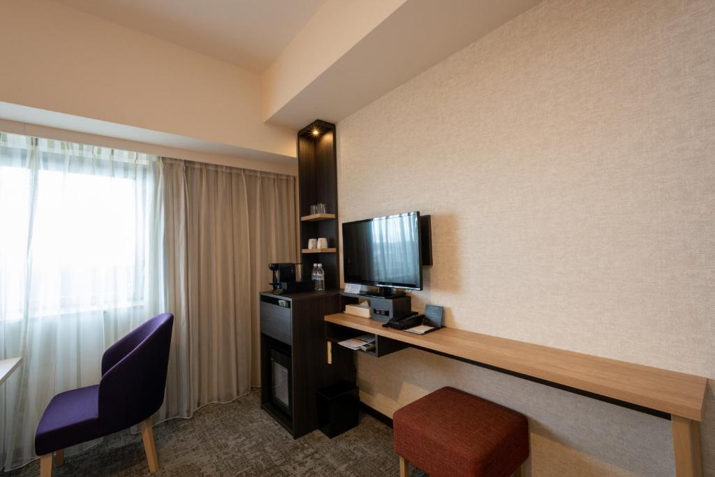 a hotel room with a desk with a tv and a chair at Hotel Kanazawa in Kanazawa