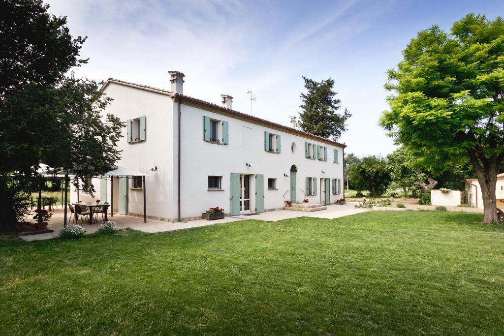 a large white house with a grass yard at Molino Monacelli Country House in Fano