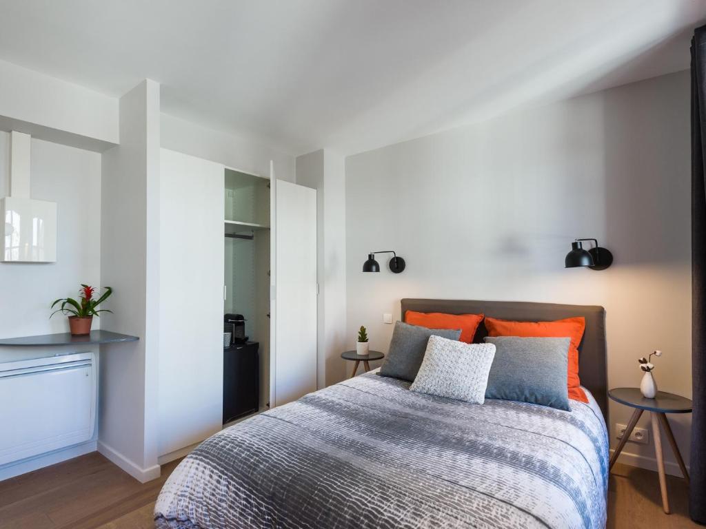 um quarto com uma cama com almofadas laranja e azul em Hyper centre chambre au calme em Lille