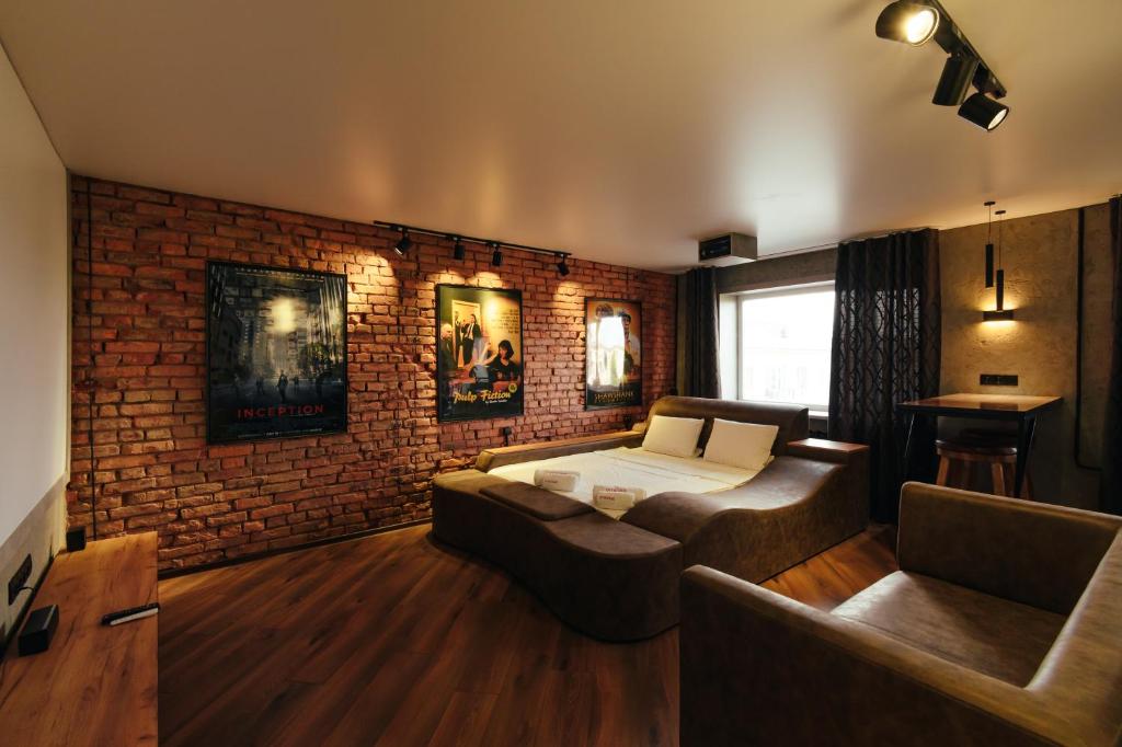 a living room with a bed and a brick wall at Квартира студия в центре Cinema in Petropavlovsk