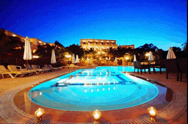 a large swimming pool with blue water at night at Crithoni's Paradise Hotel in Alinda