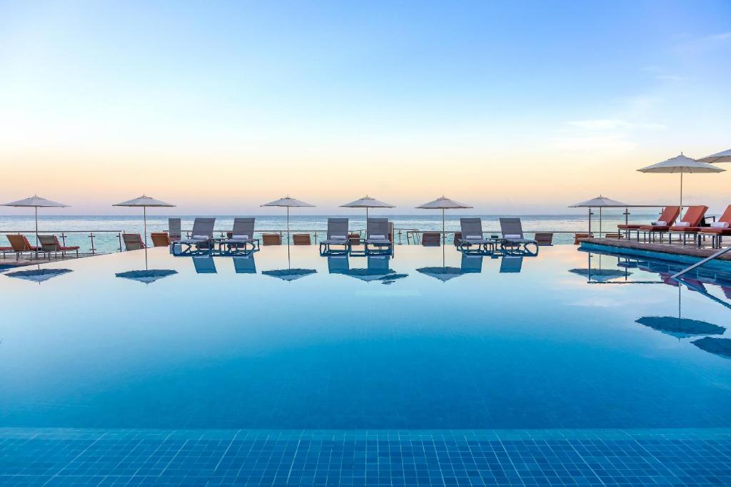 una piscina con sillas y sombrillas en la playa en Cozumel Palace-All Inclusive, en Cozumel