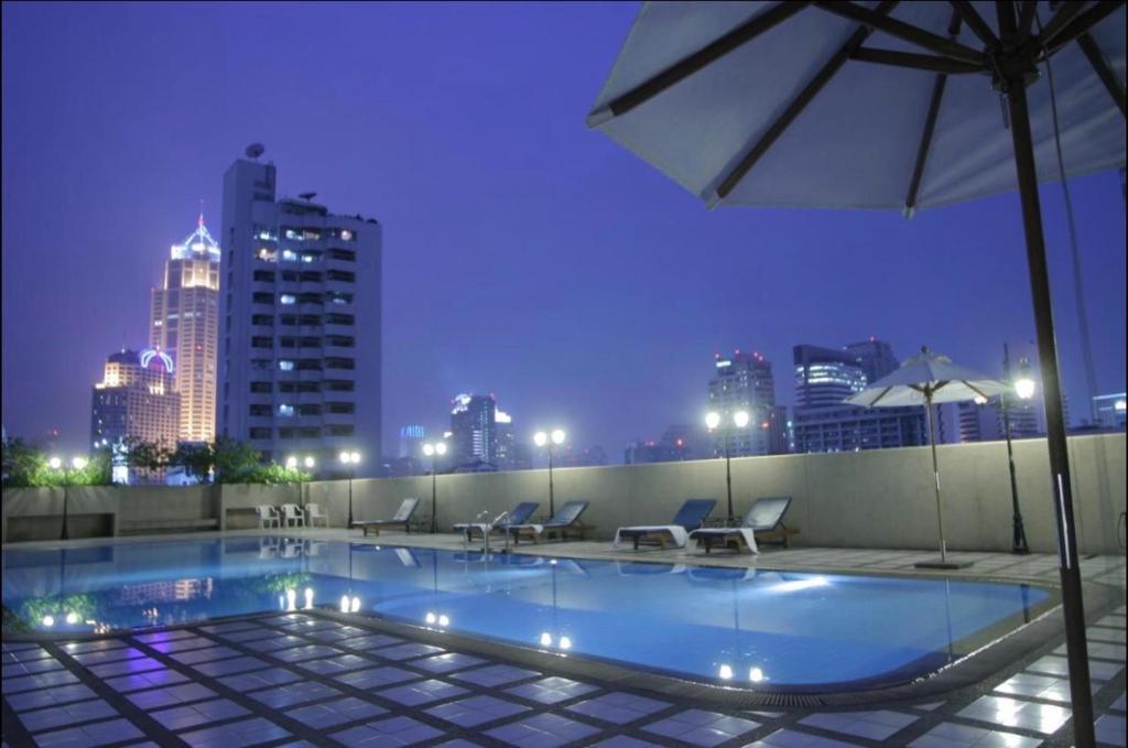 a swimming pool on top of a building with a city skyline at Omni Tower Cozy Apartment Near NANA BTS in Bangkok
