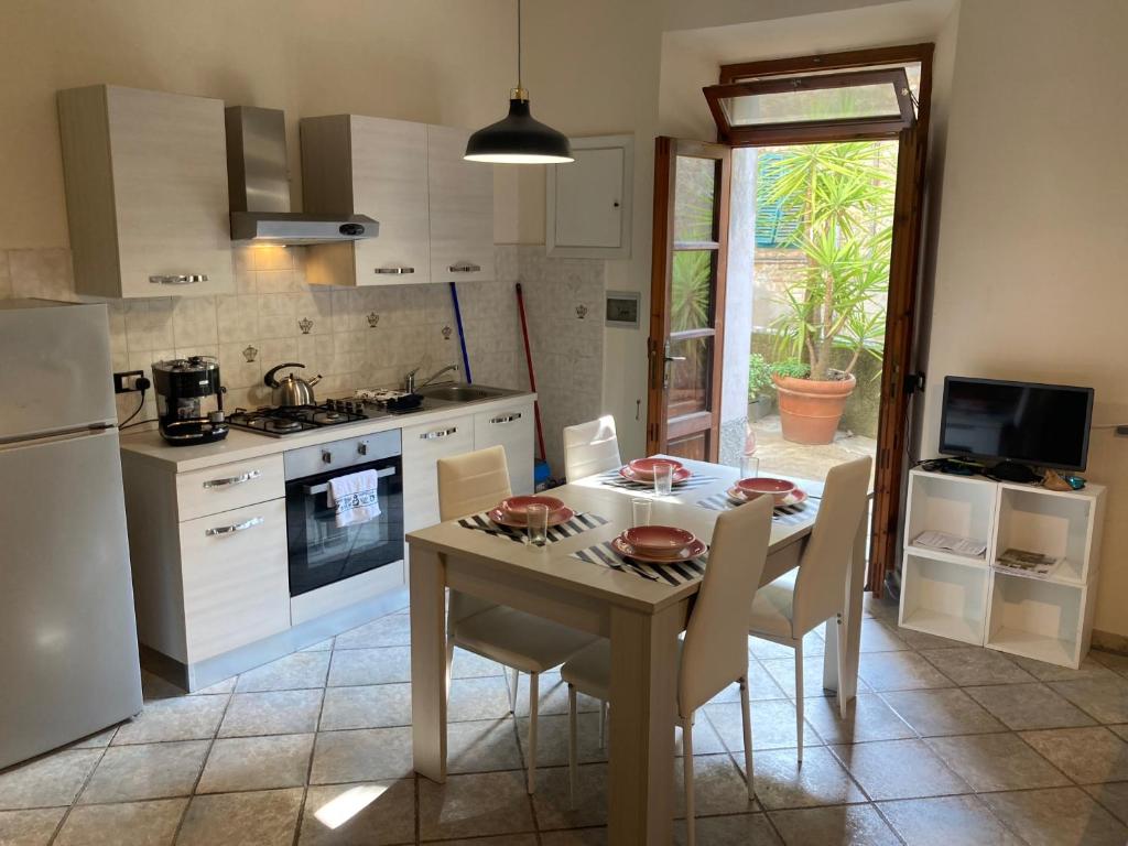 kuchnia ze stołem i krzesłami oraz kuchnia z białymi urządzeniami w obiekcie Great studio apartment in the heart of Chianni w mieście Chianni