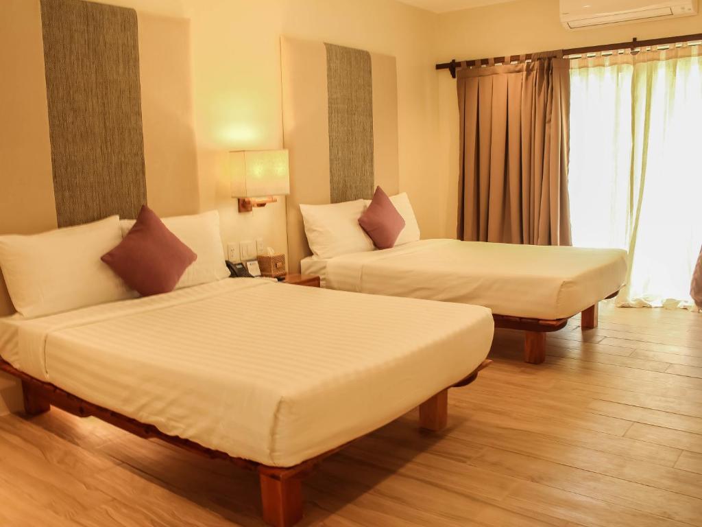 Habitación de hotel con 2 camas y ventana en Bluewater Panglao Resort en Panglao City