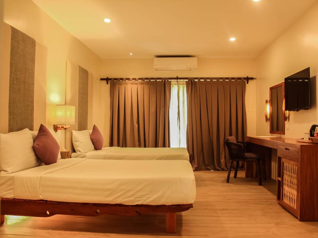a hotel room with two beds and a television at Bluewater Panglao Beach Resort in Panglao Island