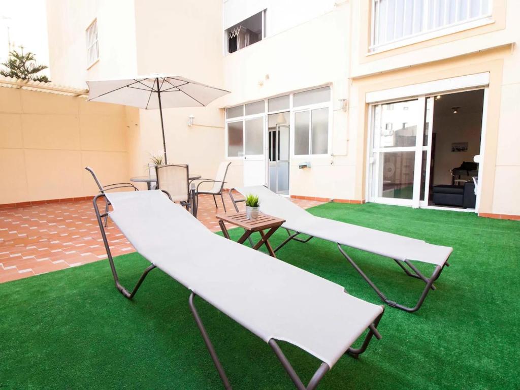 een patio met 2 witte stoelen en een parasol bij Holidays2Malaga Plaza de Toros Vieja & terrace & optional parking in Málaga