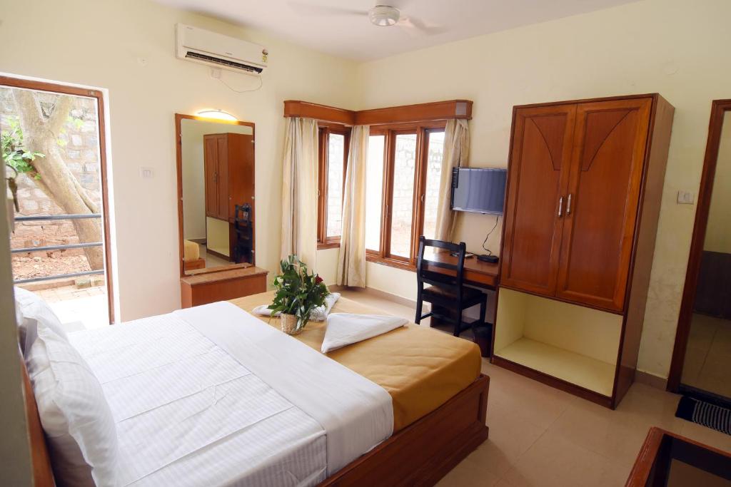 Schlafzimmer mit einem Bett, einem Schreibtisch und einem Fenster in der Unterkunft DVG Socials Retreat in Davanagere