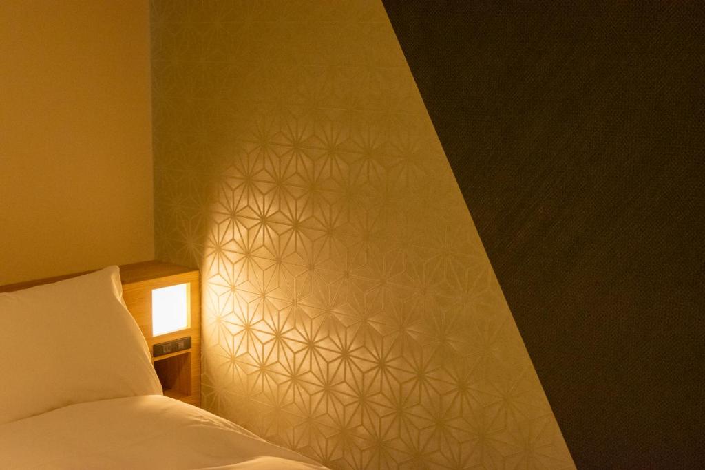 a bedroom with a bed and a wall with a white wall at Hotel Kanazawa in Kanazawa