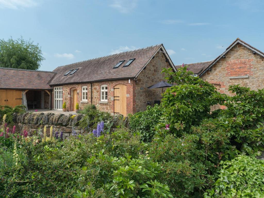 une ancienne maison en briques avec un jardin en face de celle-ci dans l'établissement Swallows Cottage, à Harley