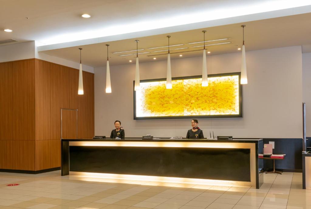 two people sitting at a reception desk in a lobby at Hotel Kanazawa in Kanazawa