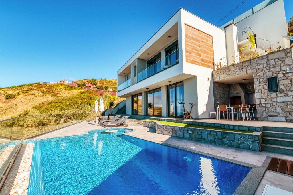 a villa with a swimming pool and a house at The Cliffhouse by LovelyStay in Fajã da Ovelha