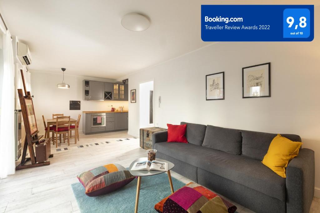 ein Wohnzimmer mit einem grauen Sofa und einer Küche in der Unterkunft Apartment Paha-Paha modern & full of light with free parking in Rijeka