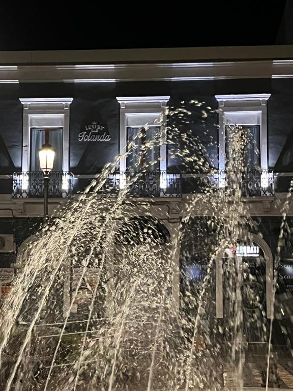 uma fonte em frente a um edifício à noite em Luxury B&B Iolanda em Catânia