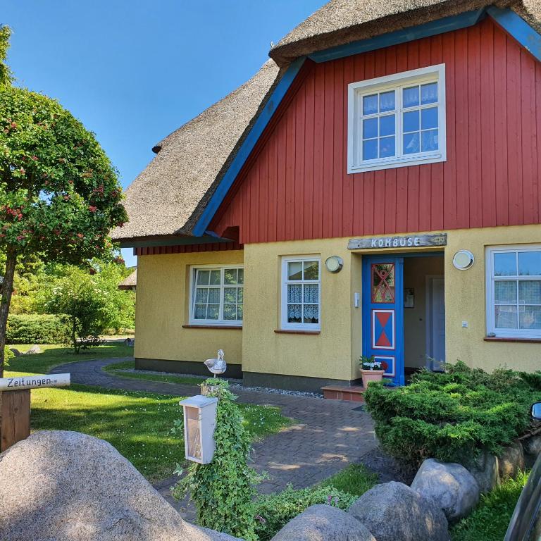 a red and yellow house with a red roof at "Kombüse" by Ferienhaus Strandgut in Born