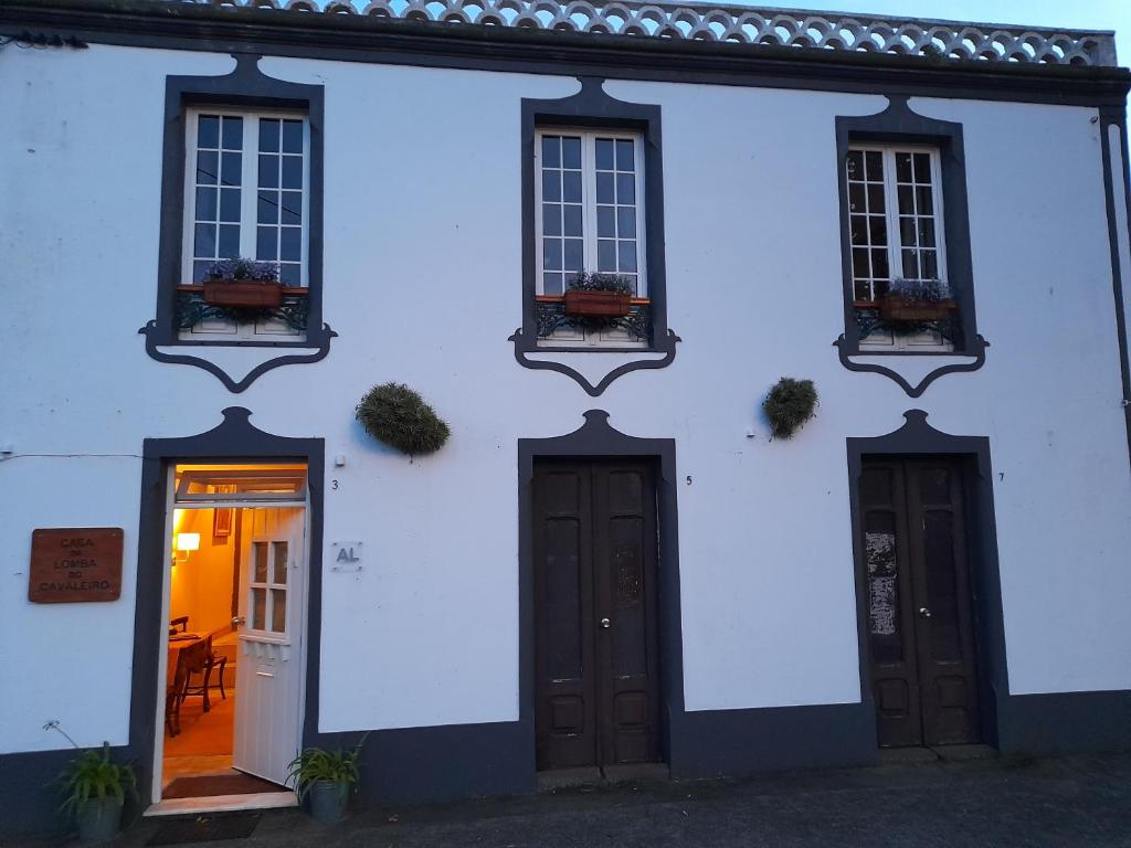 a white house with two doors and windows at Casa da Lomba do Cavaleiro in Povoação