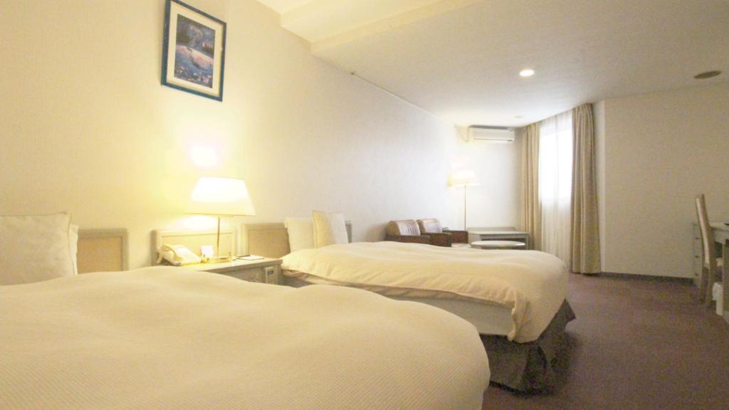 una camera d'albergo con due letti e una finestra di Hotel New Century a Città di Okinawa