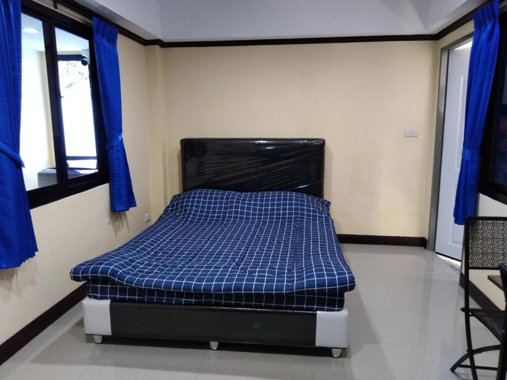 Cama pequeña en habitación con cortinas azules en SRS3 STUDIO APARTMENT en Ban Bang Kha
