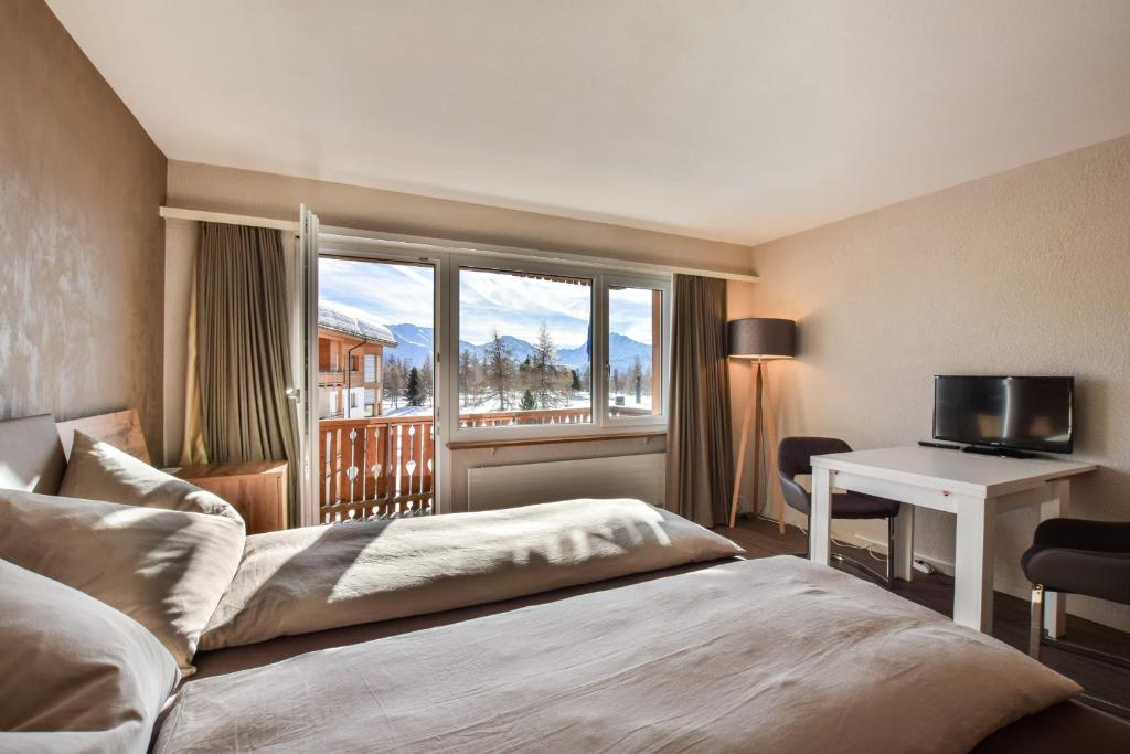 ein Schlafzimmer mit einem Bett, einem Schreibtisch und einem Fenster in der Unterkunft Rhodania 56 in Riederalp