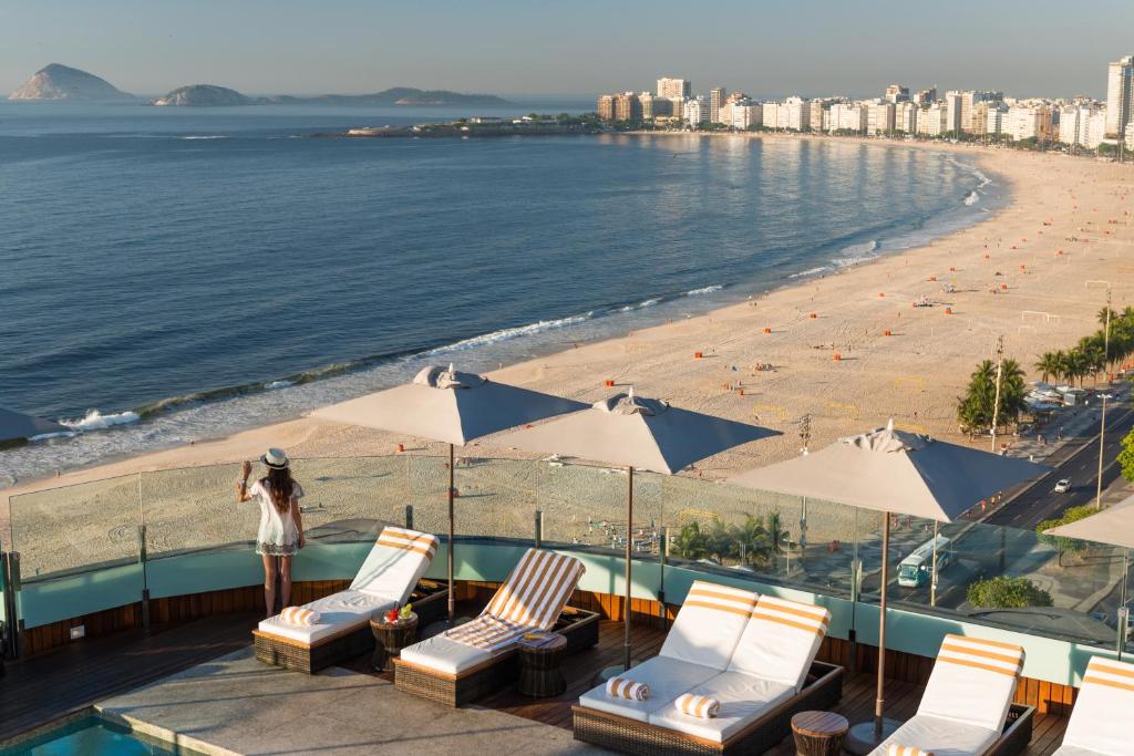 una mujer parada junto a una playa con sillas y sombrillas en PortoBay Rio de Janeiro, en Río de Janeiro