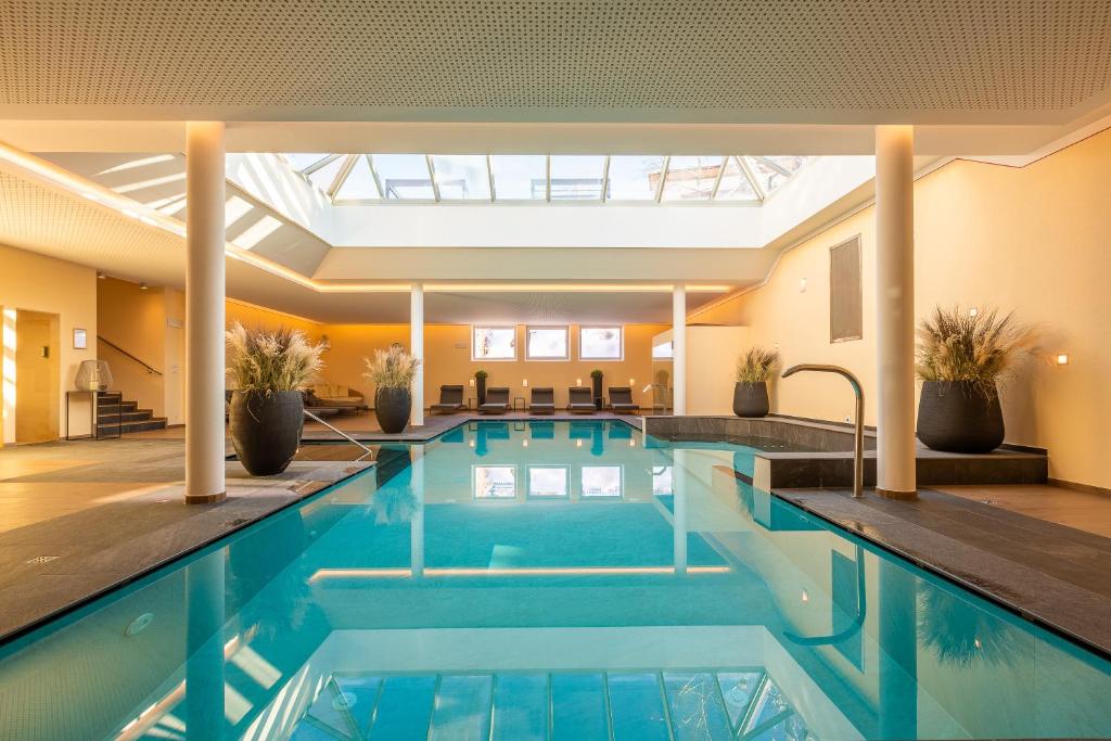 a swimming pool in a hotel with a large building at Hotel Villa Stefania in San Candido