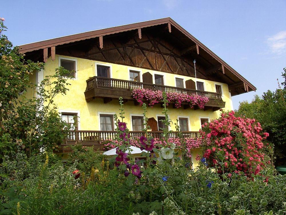 a yellow house with a balcony and flowers at Köllhof in Höslwang