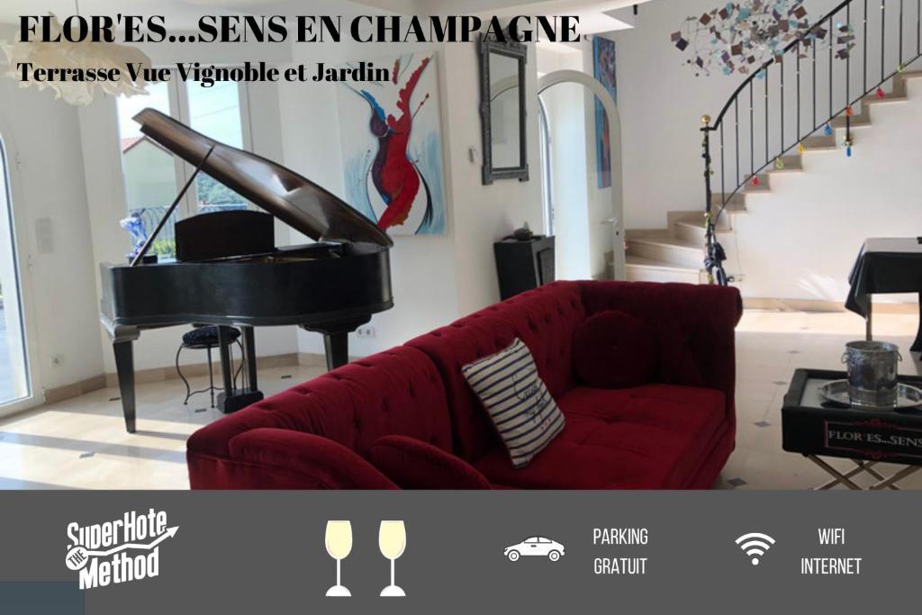 ein Wohnzimmer mit einem roten Sofa und einem Klavier in der Unterkunft FLORESSENS EN CHAMPAGNE Terrasse privative sur le vignoble in Fleury-la-Rivière