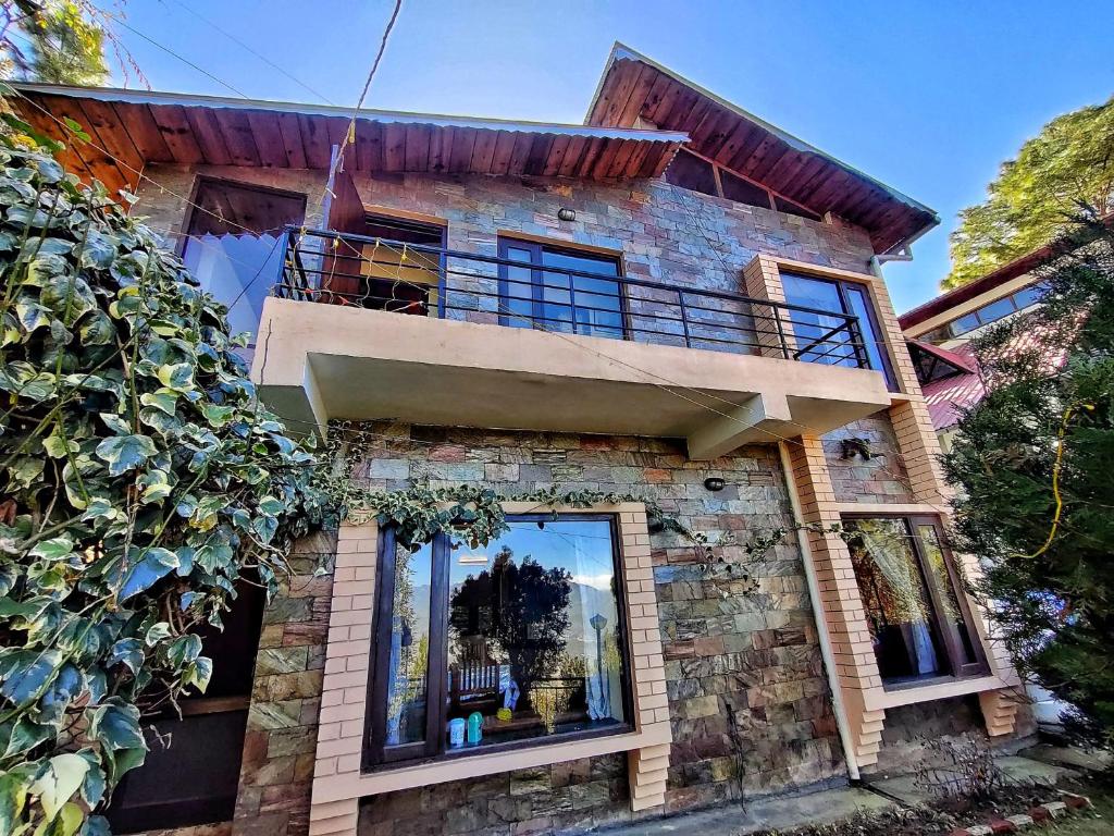 a brick house with a balcony on top of it at Mysa by Meraki - Entire Villa with Himalayan Views in Rānīkhet
