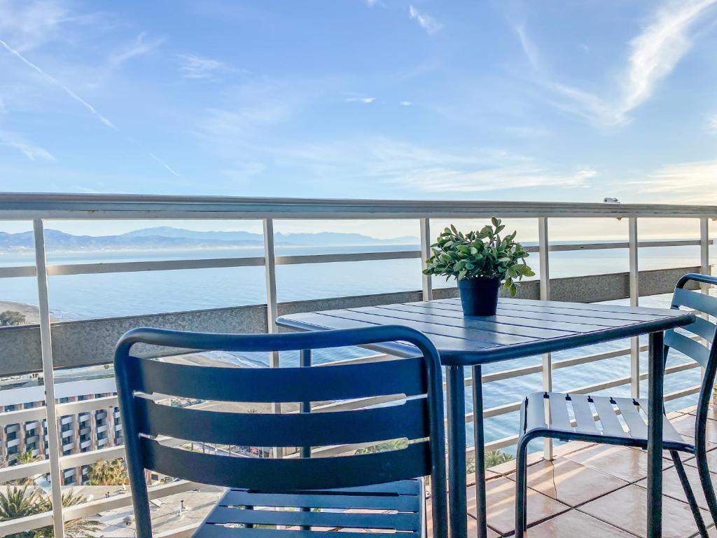 uma mesa e cadeiras numa varanda com vista para o oceano em Apartamento moderno con vistas panorámicas em Torremolinos