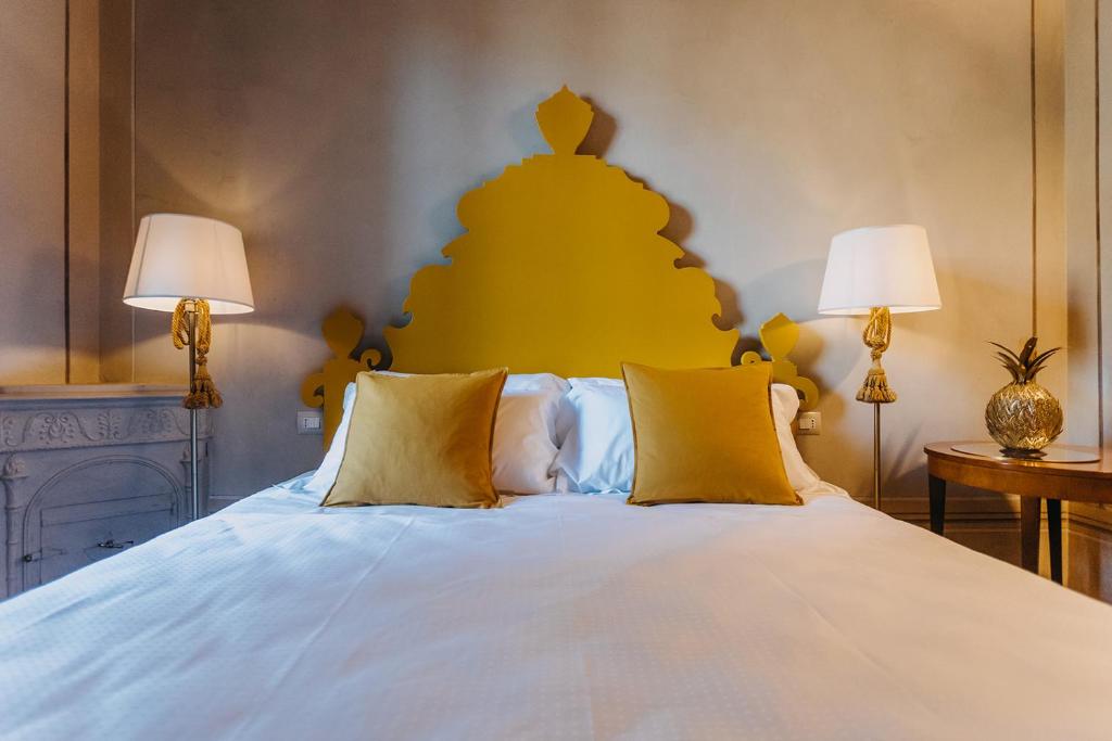 a bedroom with a large white bed with two lamps at Palazzo Feroci - Residenza d'epoca in Pisa