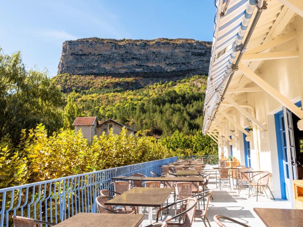 un balcone con tavoli e sedie e una montagna sullo sfondo di Village Club Les Lavandes - Neaclub a Rémuzat