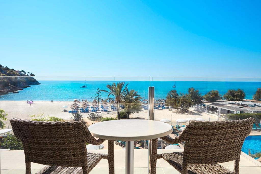 una mesa y sillas con vistas a la playa en Universal Hotel Castell Royal en Canyamel