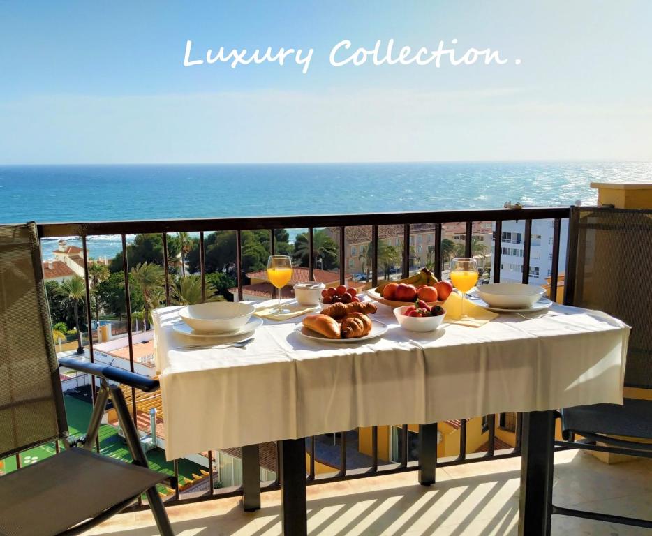 una mesa con comida y bebida en un balcón con vistas al océano en New 2023 Don Gustavo, Beach Front, Sea Views, en Benalmádena