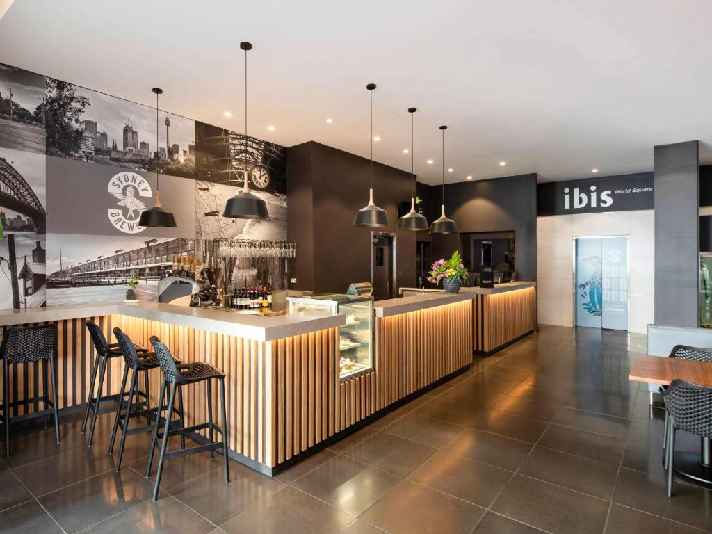 a restaurant with a bar with chairs and tables at ibis Sydney World Square in Sydney