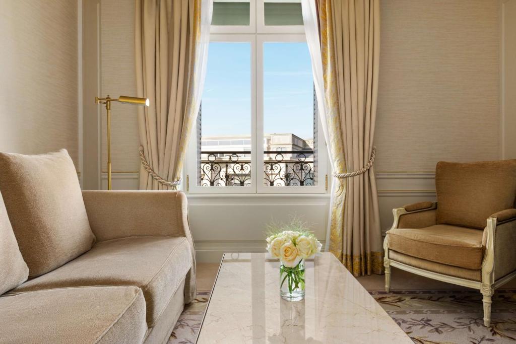 a living room with a couch and a vase of flowers on a table at Shangri-La Paris in Paris
