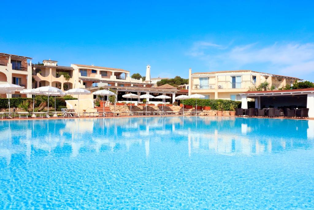 una grande piscina con sedie e ombrelloni di Grand Hotel In Porto Cervo a Porto Cervo