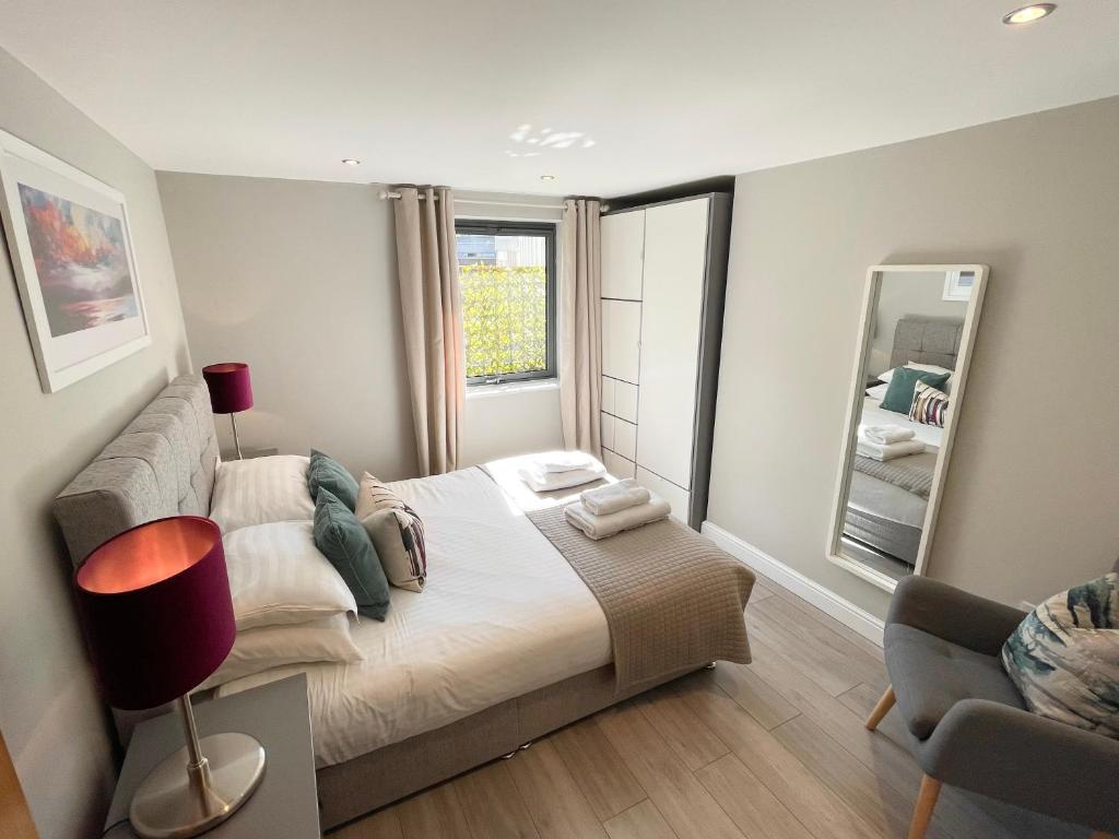 a bedroom with a bed and a lamp and a mirror at Urban Living's - The Wesley Beautiful City Centre Apartment with Balcony in Oxford