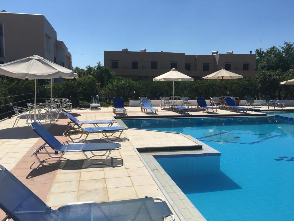 una piscina con sedie a sdraio e ombrelloni di Oasis Guesthouse a Chania