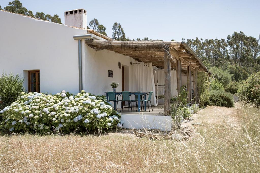 a house with chairs and flowers in front of it at Muxima - Aljezur in Aljezur