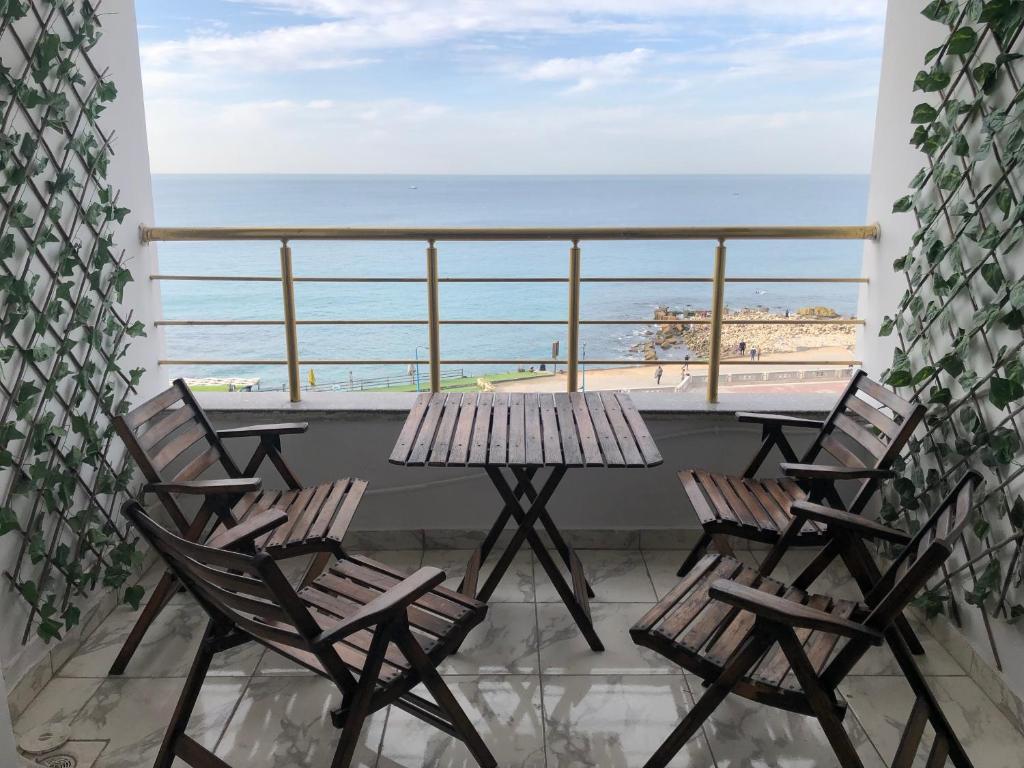 een balkon met stoelen en een tafel en uitzicht op het strand bij Santorini Seafront Stay in Alexandrië