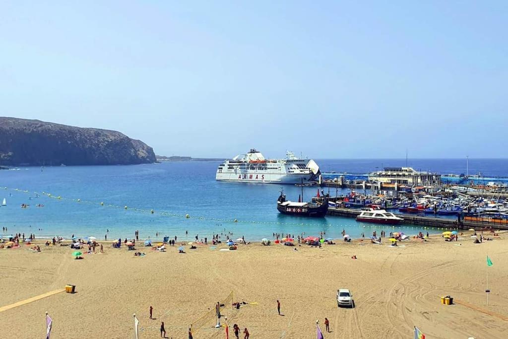 un groupe de personnes sur une plage avec un bateau de croisière dans l'établissement Silver Beach Tenerife, à Los Cristianos