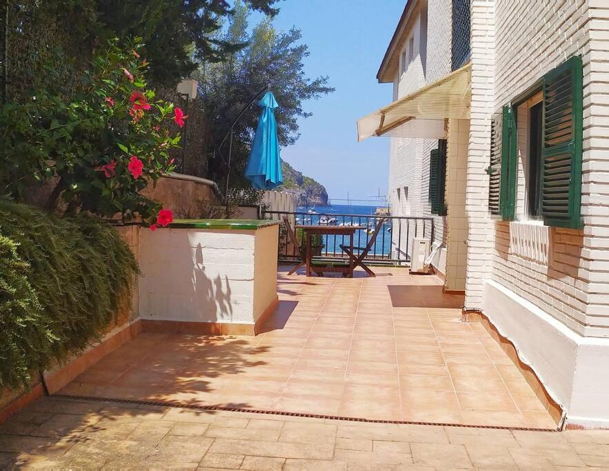 a patio with a blue umbrella and a table with a table at Port de Sóller Promenade Apartment. in Port de Soller