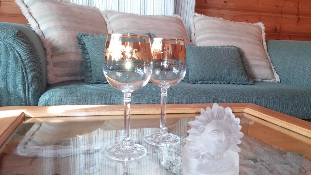 two wine glasses sitting on a table in front of a couch at Vila Dovilas in Palanga