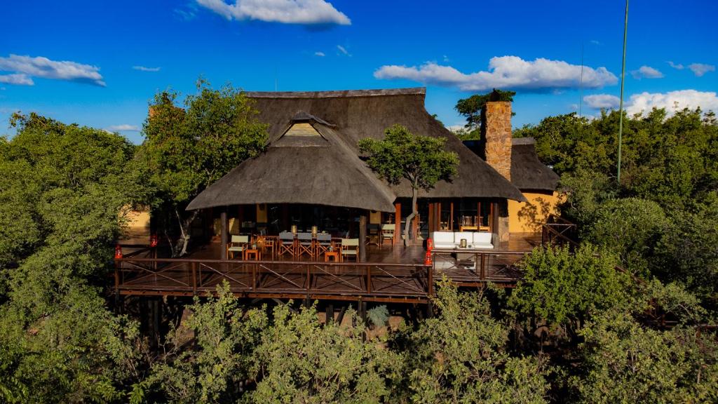 uma casa com telhado de palha na floresta em Nungubane Game Lodge em Welgevonden Game Reserve