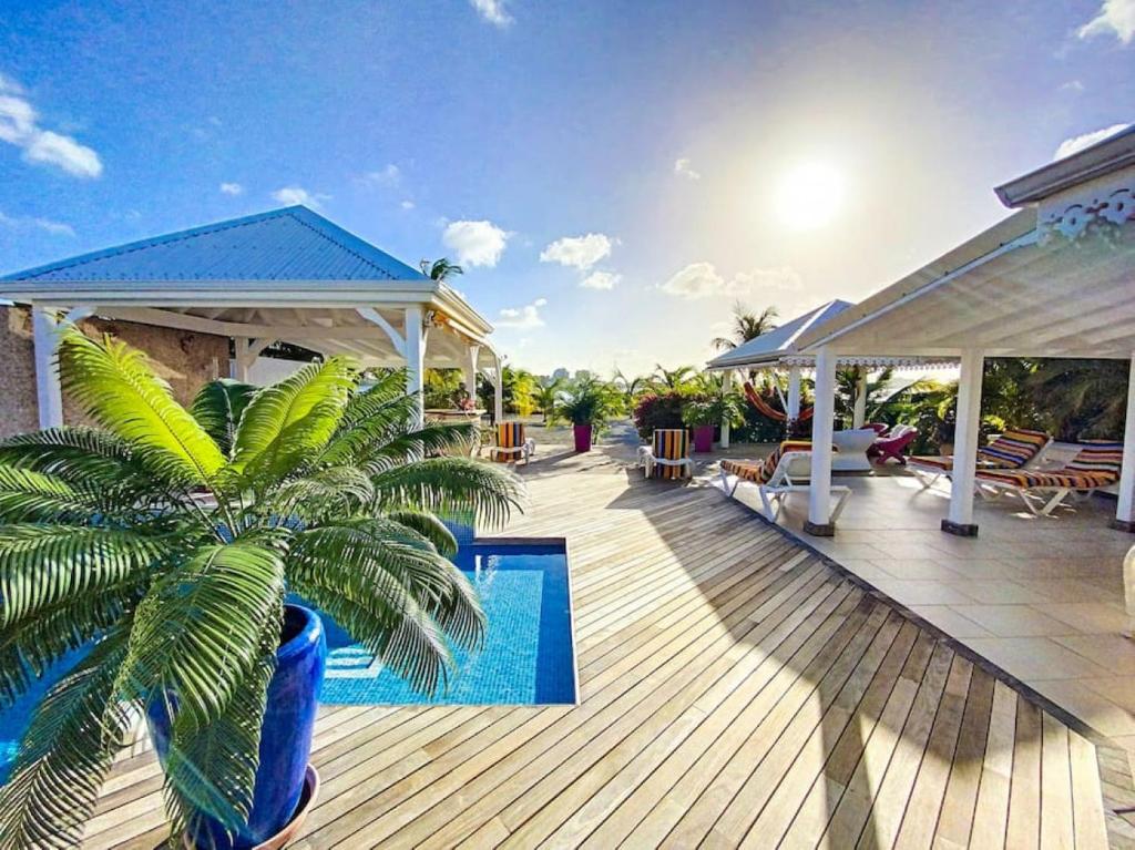 una terrazza in legno con una palma accanto alla piscina di Villa Marie, swimming pool, beach, pontoon and jacuzzi, all private a Baie Nettle