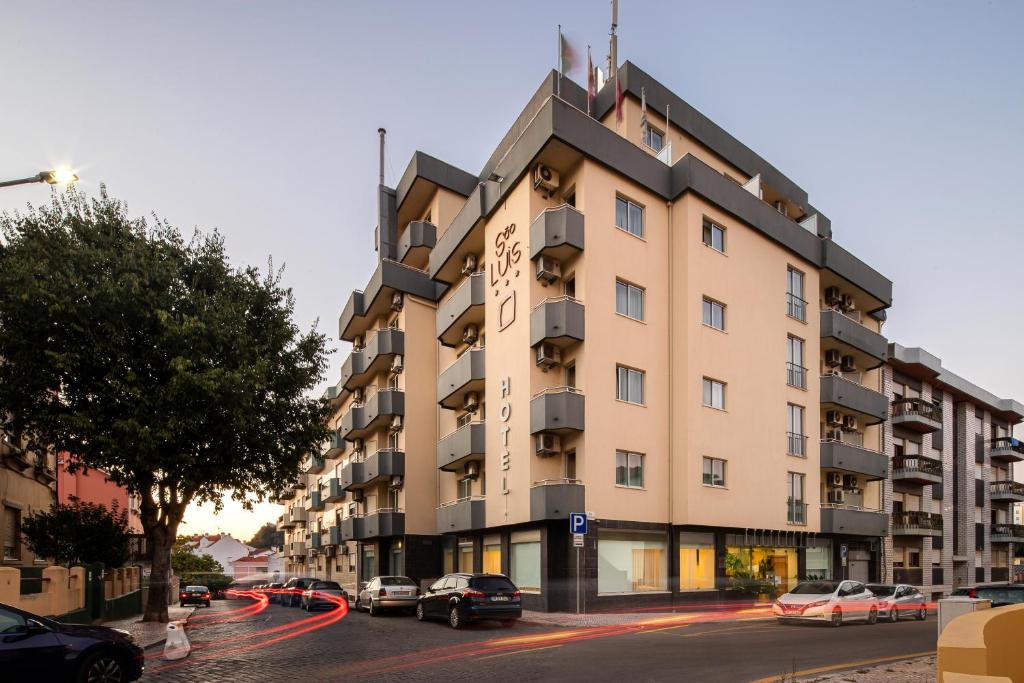 un edificio alto con coches estacionados frente a él en Hotel Sao Luis, en Leiria